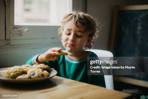 boy looking at his homemade cookie while eating - toddler eating sandwich stock pictures, royalty-free photos & images