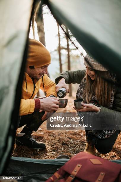 couple is drinking tea in front of their camping tent during sunny winter day - flask stock pictures, royalty-free photos & images