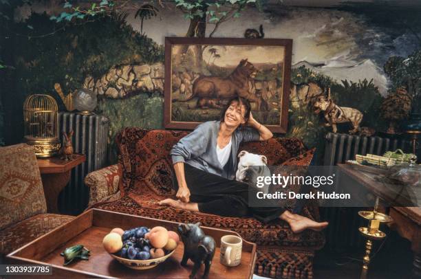 Jane Mallory Birkin, OBE poses barefoot on a sofa covered with an oriental woven carpet with her British Bulldog Dora by her side in the salon of her...