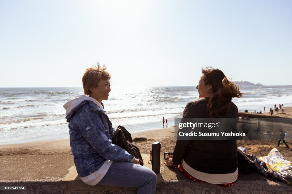 Two women are walking along the beach on a winter holiday on a short trip.