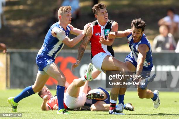 Josh Battle of the Saints kicks the ball under pressure from Jack Ziebell of the Kangaroos and Robbie Tarrant of the Kangaroos during the AFL...