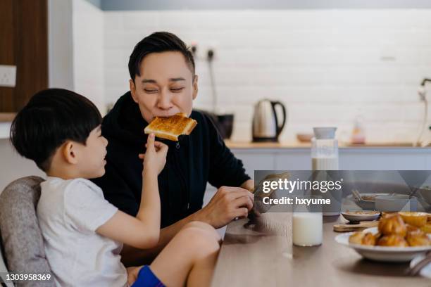 aziatische chinese vader en zoon die ontbijten samen - eating bread stockfoto's en -beelden