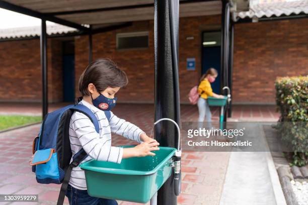 jongen die zijn handen bij de school tijdens de covid-19pandemie wast - child washing hands stockfoto's en -beelden