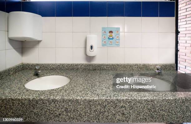 school bathroom with a poster showing the guidelines of hand washing - state of emergency sign stock pictures, royalty-free photos & images