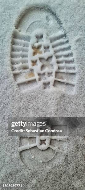 close up view of shoe print on snowy asphalt road. winter season concept. - schuhabdruck stock-fotos und bilder