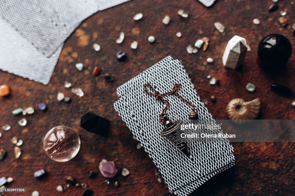 A beautiful iron pendulum lies on a deck of tarot cards on a dark background