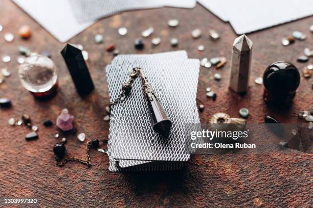 a beautiful dark pendulum lies on a deck of tarot cards on a dark background - medium group of objects - fotografias e filmes do acervo