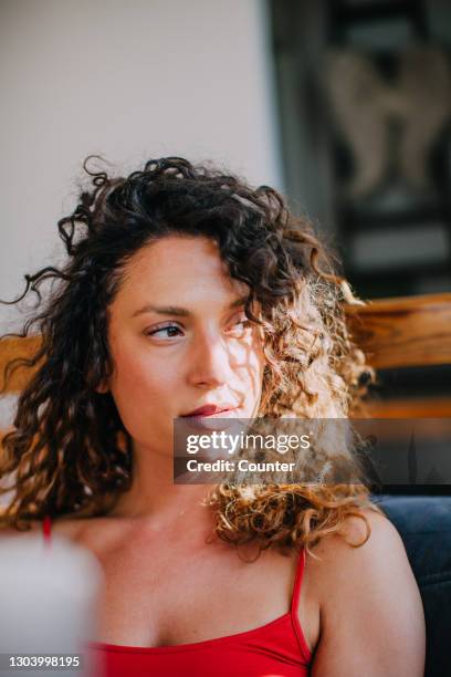 portrait of young woman in sunlight at home - candid curly hair stock pictures, royalty-free photos & images