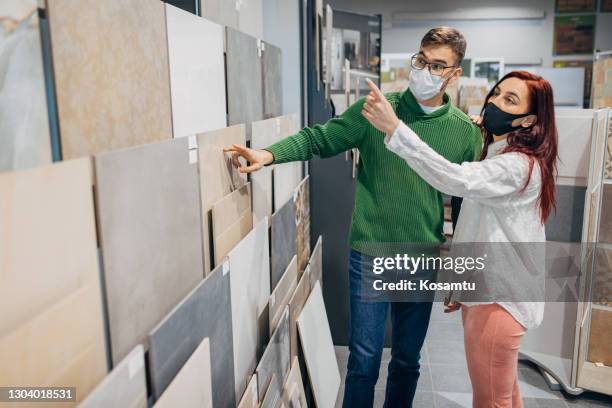 modern young couple at the store showroom, choosing the perfect tile design for their new home - tile showroom stock pictures, royalty-free photos & images