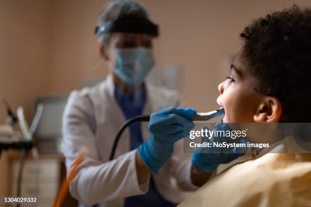 grauhaarige zahnärztin arbeitet - zahnkaries stock-fotos und bilder