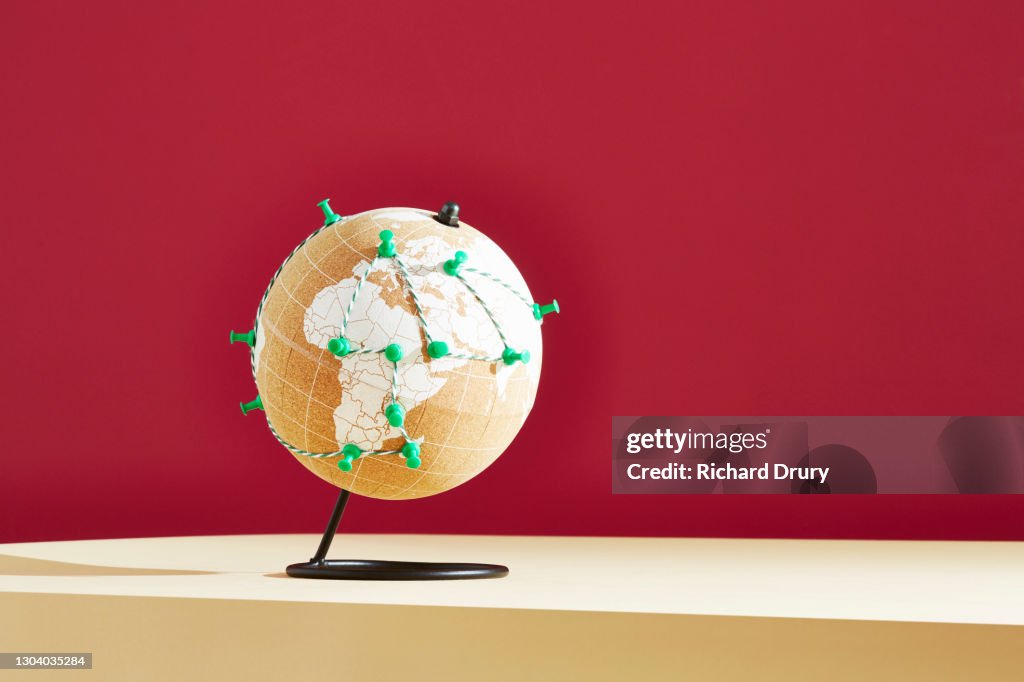 A world globe with a journey marked in green string and pins
