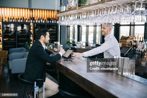 businessman ordering a drink at the bar - business class lounge stock pictures, royalty-free photos & images