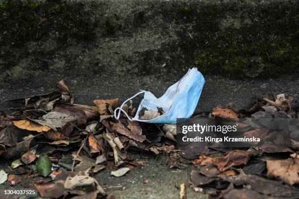medical mask thrown carelessly on the ground - masque de chirurgien photos et images de collection