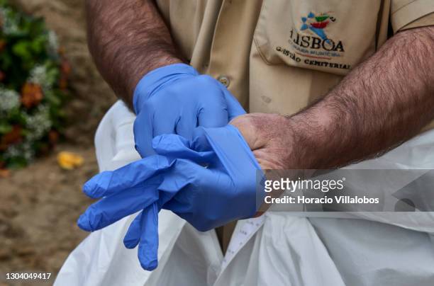 Gravedigger changes latex gloves in between burials of COVID-19 victims at Cemitério do Alto de São João during the COVID-19 Coronavirus pandemic on...