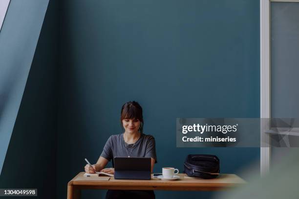 women in business: a smiling young businesswoman using a digital tablet at her office - attending stock pictures, royalty-free photos & images