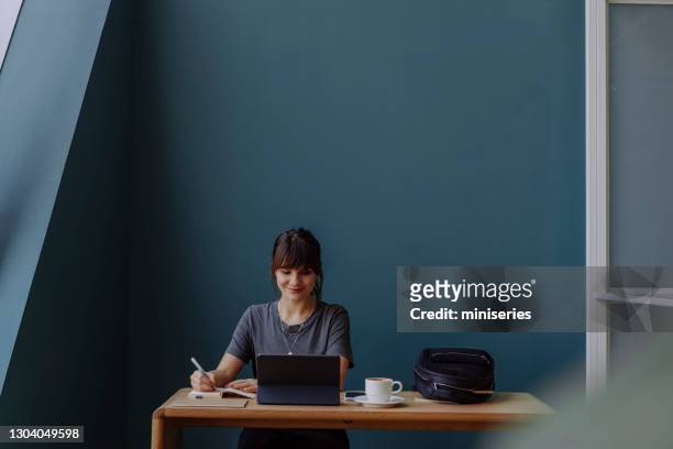 kvinnor i näringslivet: en leende ung affärskvinna som använder en digital surfplatta på sitt kontor - attendee bildbanksfoton och bilder