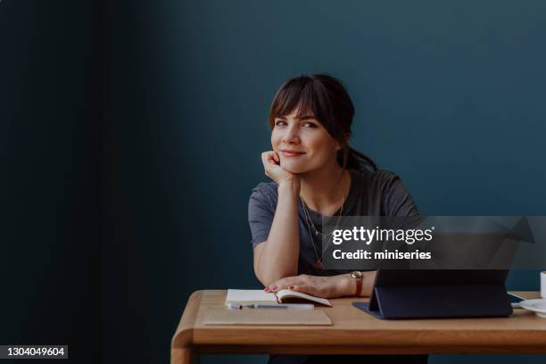 women in business: a smiling young businesswoman using a digital tablet at her office - attending webinar stock pictures, royalty-free photos & images