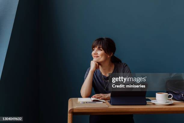 women in business: a smiling young businesswoman using a digital tablet at her office - attending webinar stock pictures, royalty-free photos & images