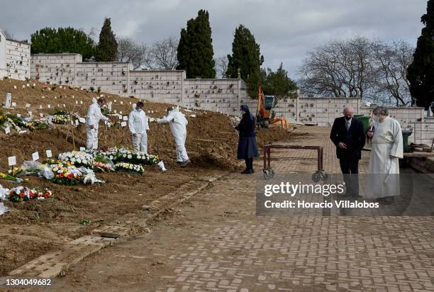 Nun stands before the burial site of a COVID-19 victim while gravediggers wearing protective gear finish their work at Cemitério do Alto de São João...