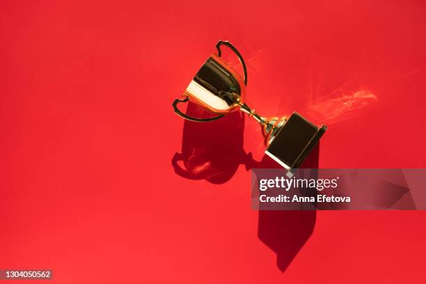 top view of metallic golden goblet on bright red background with shadow. goal achievement concept. trendy colors of the year - pride awards ceremony stock pictures, royalty-free photos & images