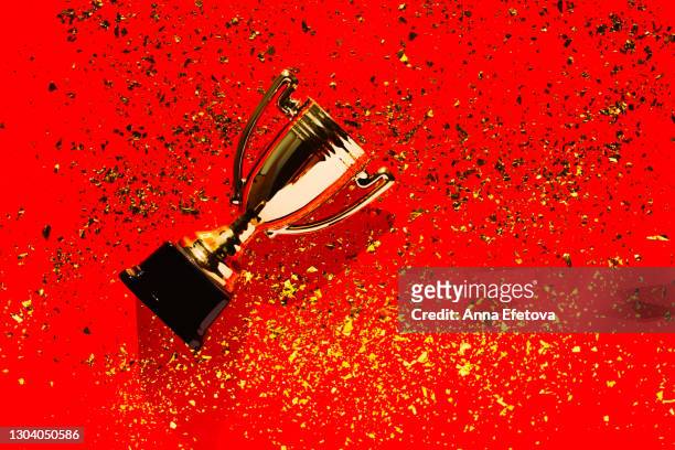 top view of metallic golden goblet on bright red background with sequin. goal achievement concept. trendy colors of the year - red tinsel stock pictures, royalty-free photos & images