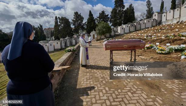 Nun stands by as a priest prays over a plastic-covered coffin of a COVID-19 victim before burial at Cemitério do Alto de São João during the COVID-19...