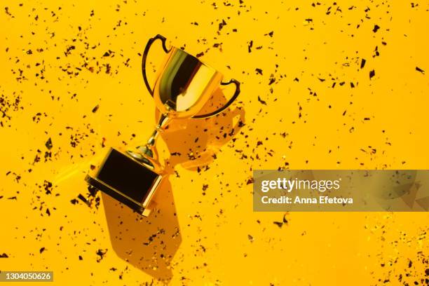 top view of metallic golden goblet on bright yellow background with sequin. goal achievement concept. trendy colors of the year - first light awards stockfoto's en -beelden