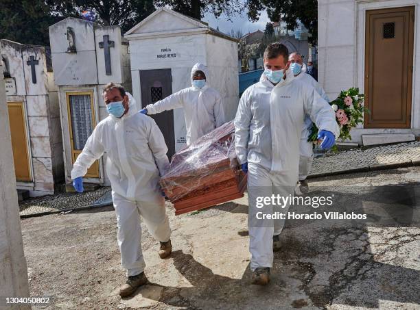 Gravediggers wearing protective gear carry a plastic-covered coffin of a COVID-19 victim before burial at Cemitério do Alto de São João during the...