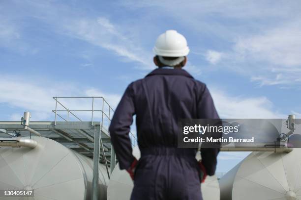 worker examining tanks outdoors - overall stockfoto's en -beelden