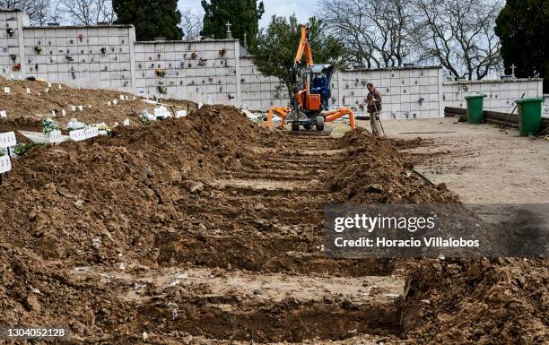 Cemetery employees operate a mechanical grave digger at Cemitério do Alto de São João during the COVID-19 Coronavirus pandemic on February 25, 2021...