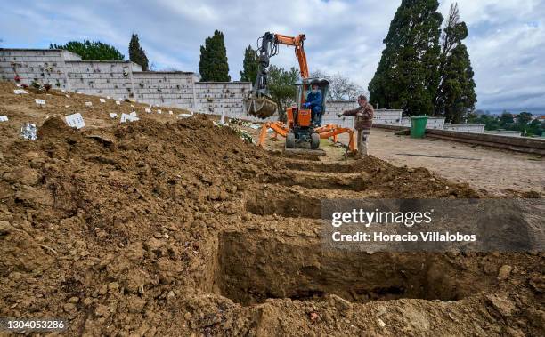 Cemetery employees operates a mechanical grave digger at Cemitério do Alto de São João during the COVID-19 Coronavirus pandemic on February 25, 2021...