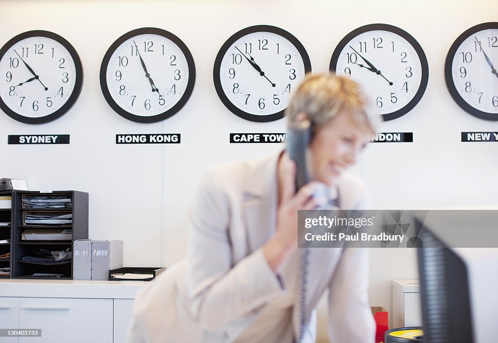 World clocks behind businesswoman in office