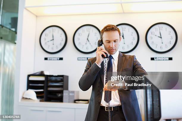 empresário verificar o relógio de escritório - landline phone imagens e fotografias de stock