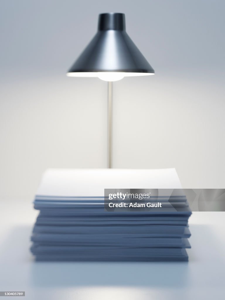 Desk lamp over stack of paper