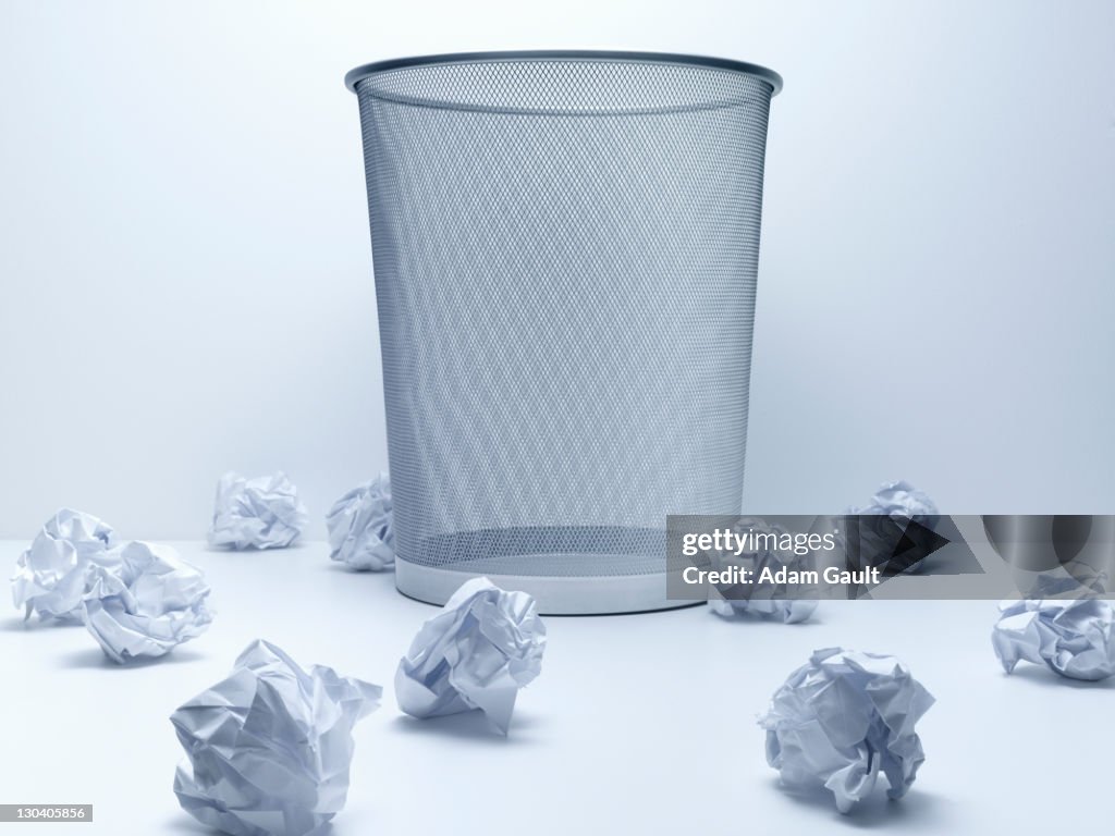 Crumpled balls of paper beside wastebasket