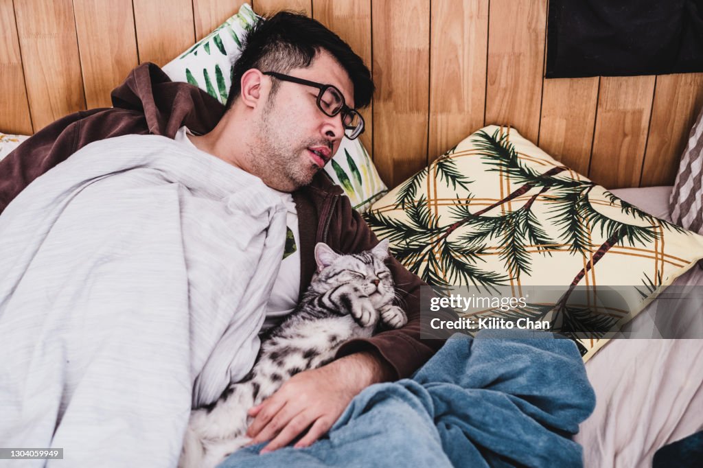 Asian man taking a nap with his cat