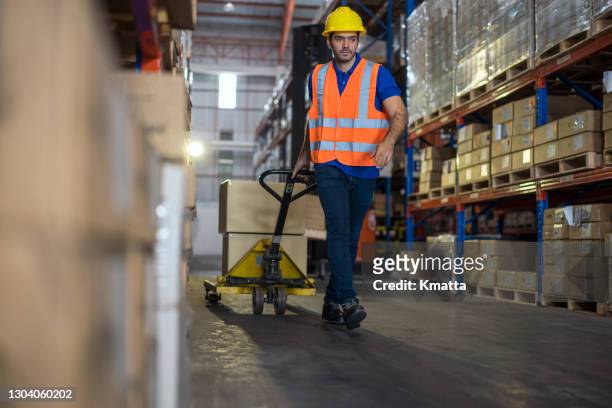 warehouse worker using hand truck to pull finish good in storage location. - chubby arab stock pictures, royalty-free photos & images