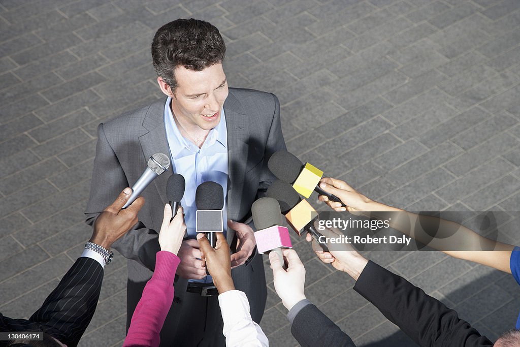 Reporters holding microphones for politician