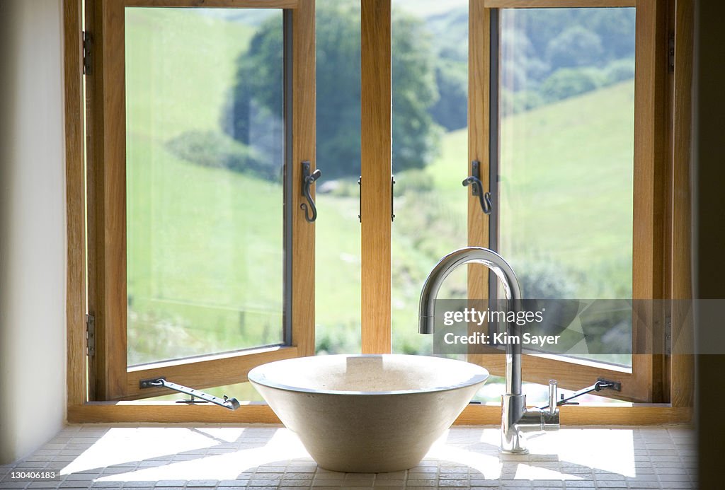 Bowl sink at window in bathroom