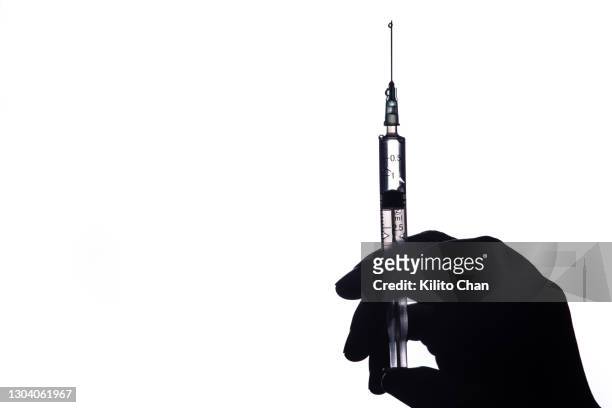 human hand holding a syringe - back lit hand stock pictures, royalty-free photos & images