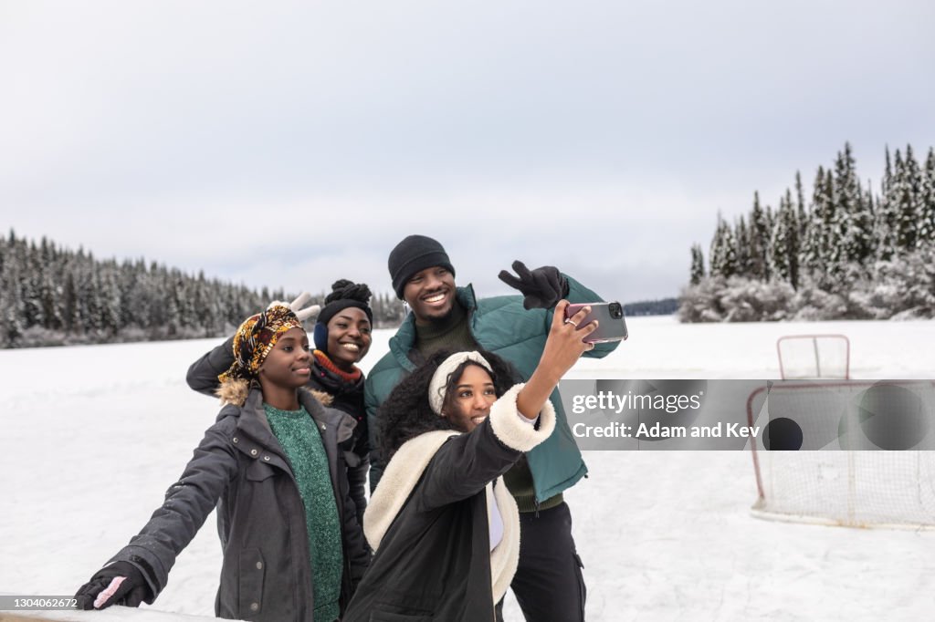 Attractive group of friends pose for selfie beside frozen lake