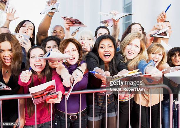 fans offering notepads for celebrity's signature behind barrier - hand over mouth stock pictures, royalty-free photos & images