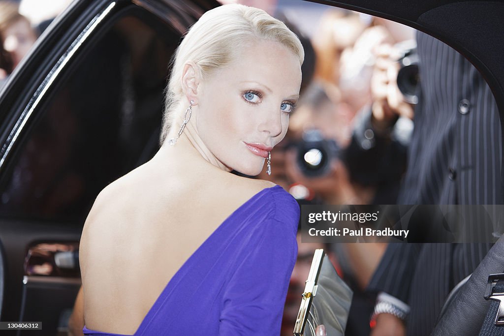Celebrity emerging from car towards paparazzi