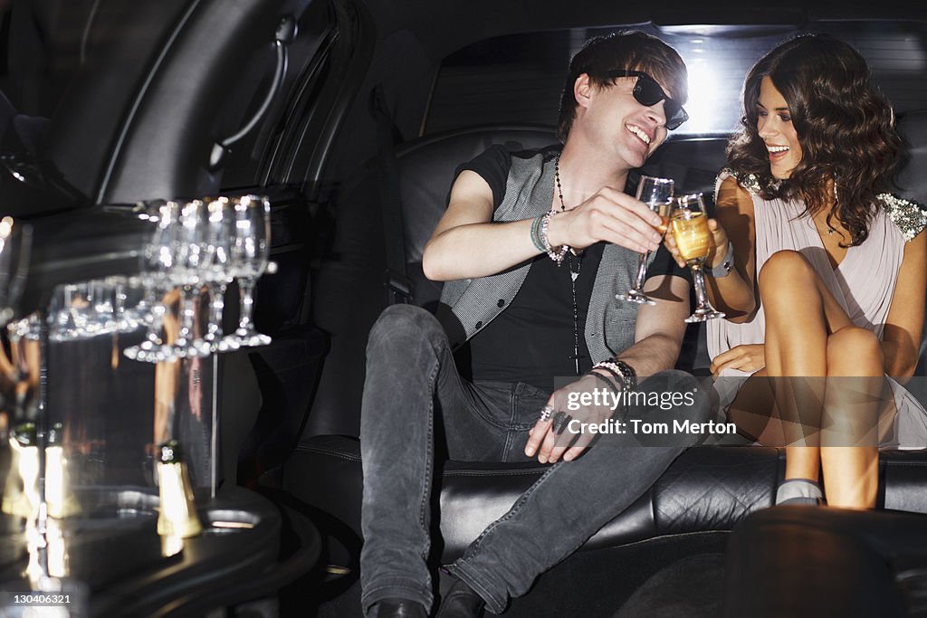 Couple toasting each other in backseat of limo