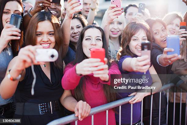 fans taking pictures with cell phone behind barrier - groupie stock pictures, royalty-free photos & images