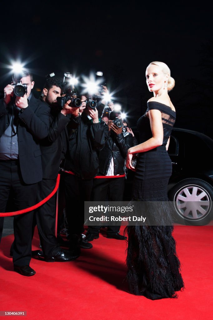 Celebrity posing for paparazzi on red carpet