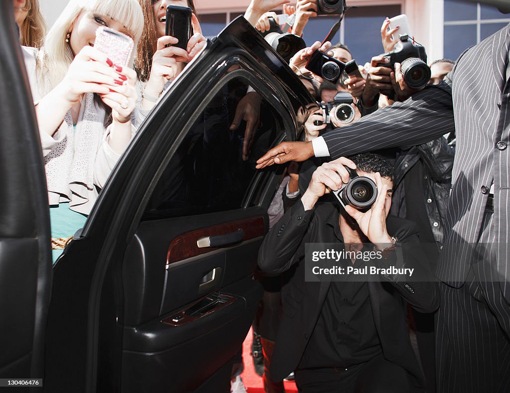 Paparazzi and fans taking photos inside car door