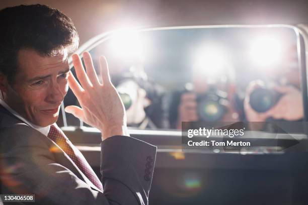 politician shielding himself from paparazzi - camera flashes stock pictures, royalty-free photos & images