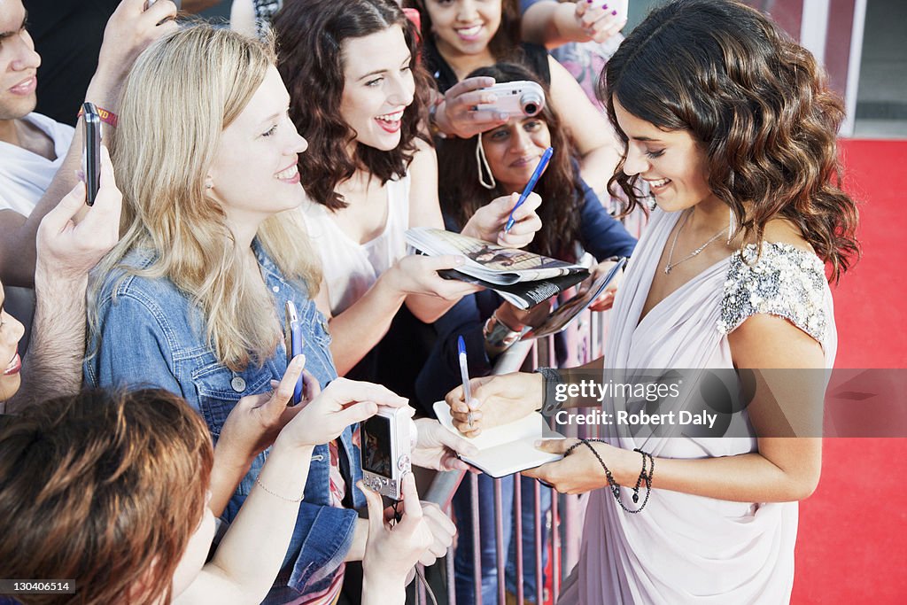 Celebrity signing autographs on red carpet