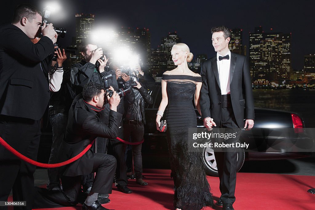 Celebrities posing for paparazzi on red carpet